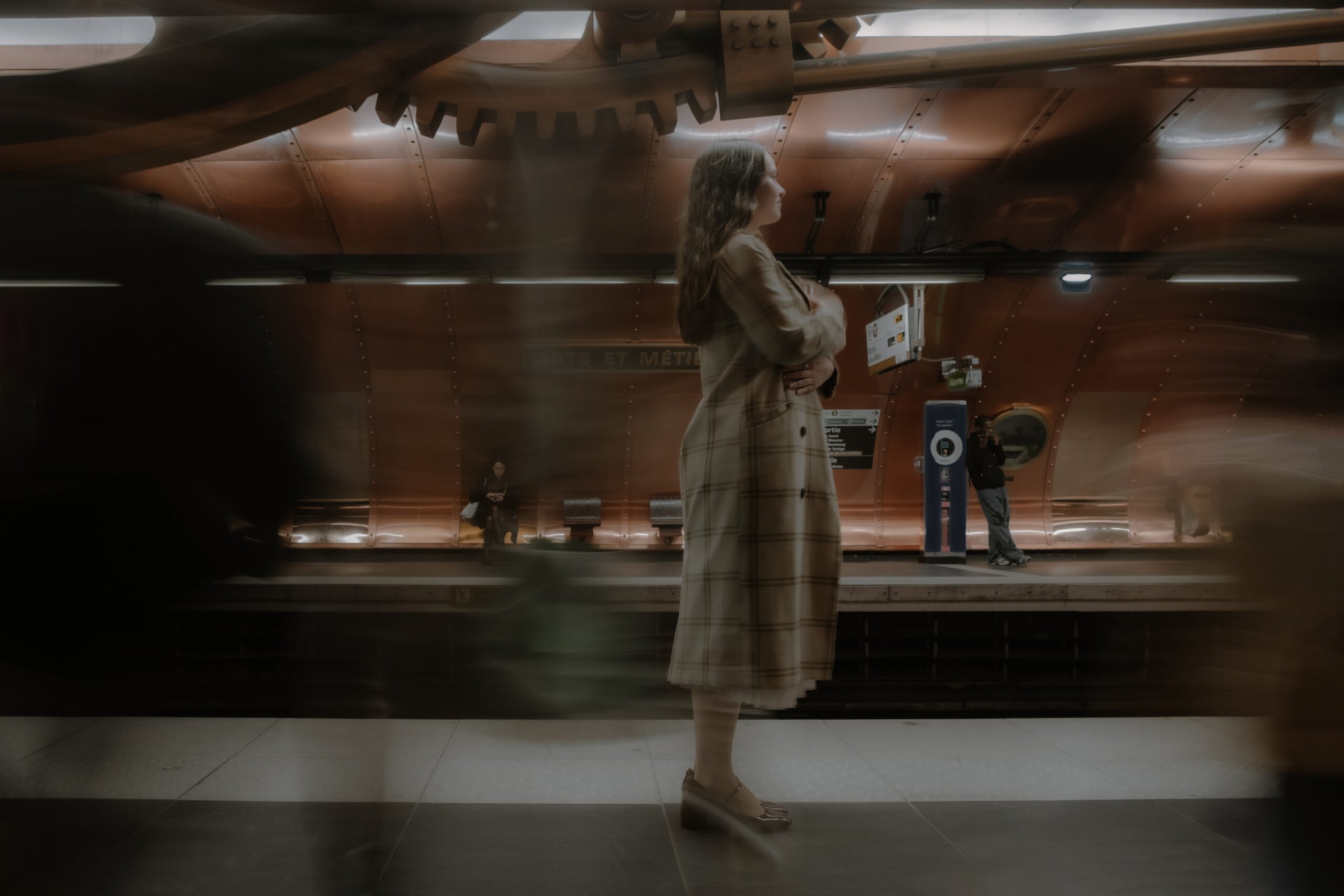 A woman waits in a Paris metro station, surrounded by motion blur of passing people.