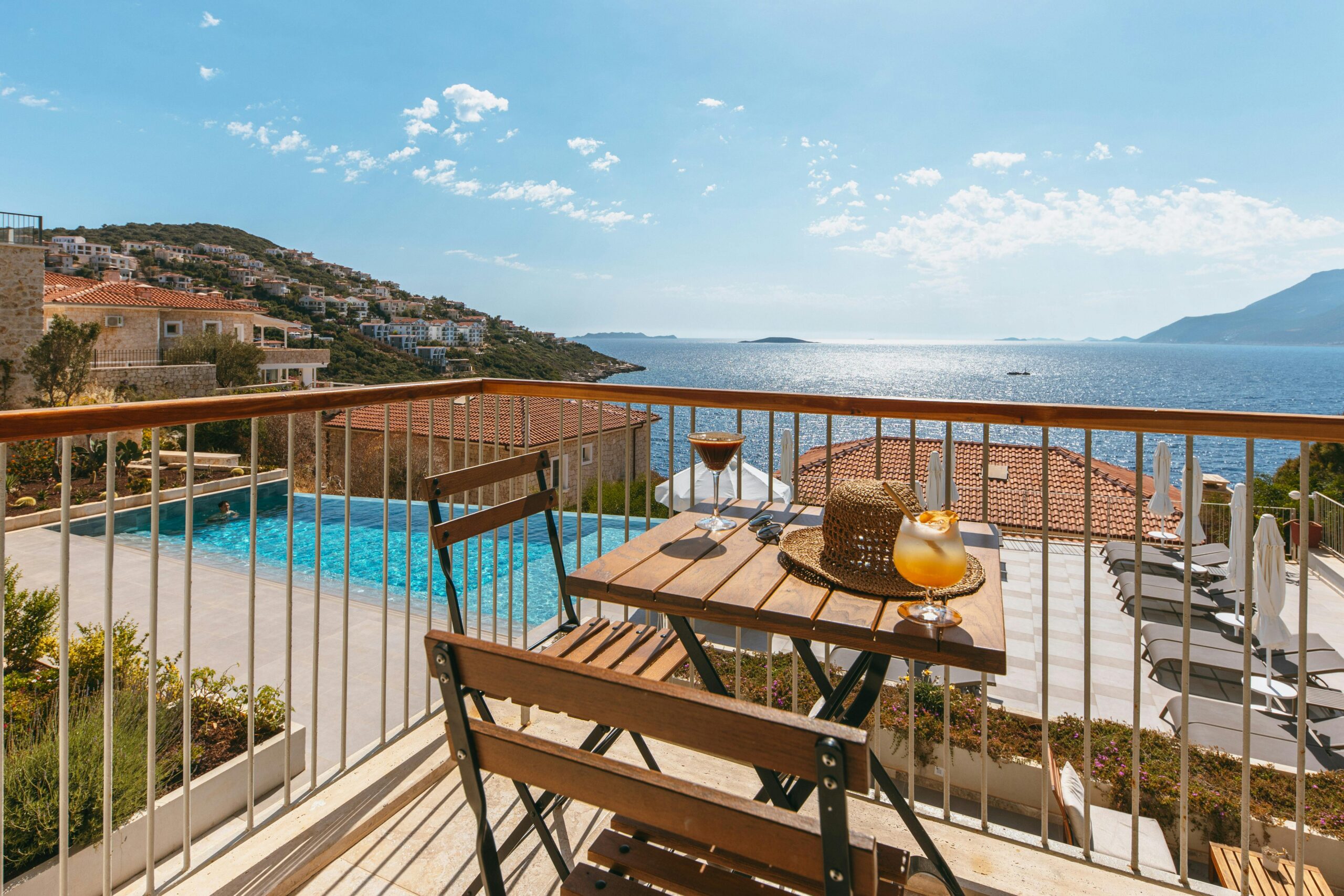 Enjoying summer drinks on a sunny seaside balcony with stunning ocean views.