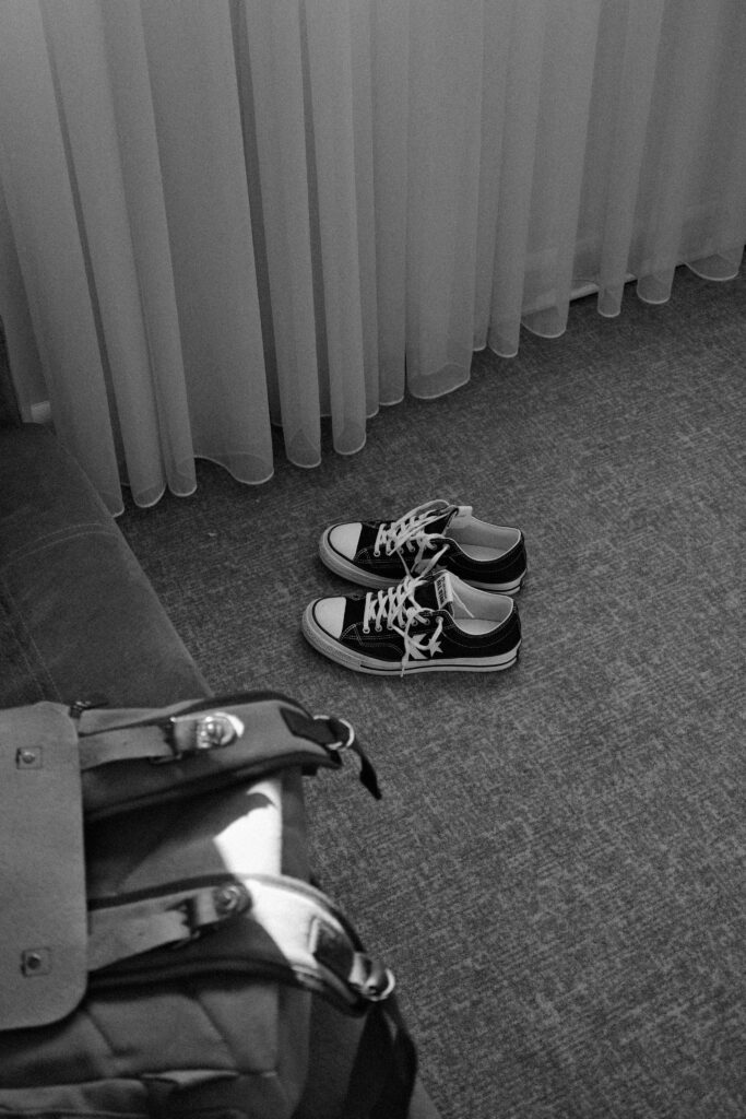 Pair of black and white sneakers next to a bag indoors.