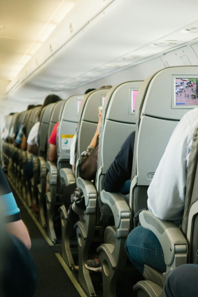 View of passengers seated in an airplane cabin, focusing on seatbacks and screens.