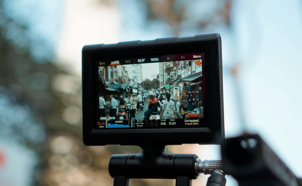 Close-up of a camera monitor showing a bustling street market scene in daylight.