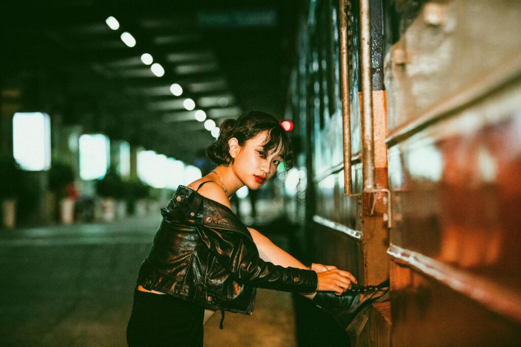 Chic woman posing at night near a train in Hanoi, exuding modern fashion vibes.