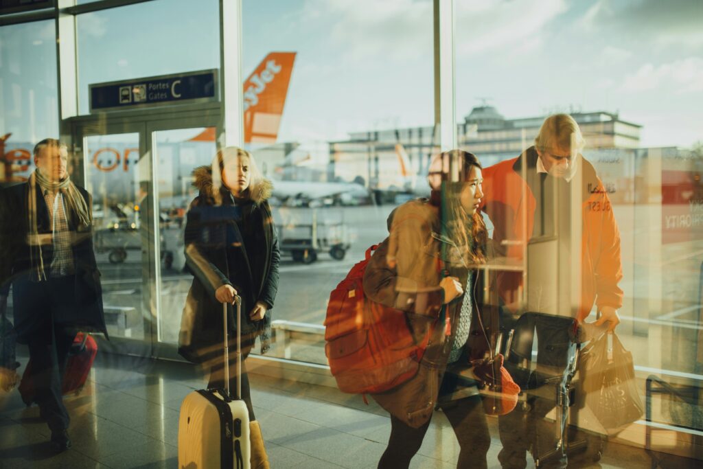 Passengers moving through an airport gate area with visible airplanes outside.