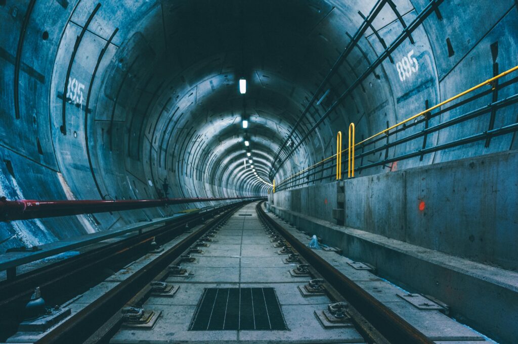 A perspective view of an underground subway tunnel with visible railway tracks.