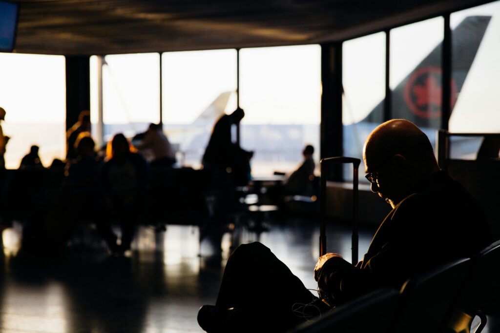 Passengers silhouetted against sunset light at an airport terminal, showcasing travel anticipation.