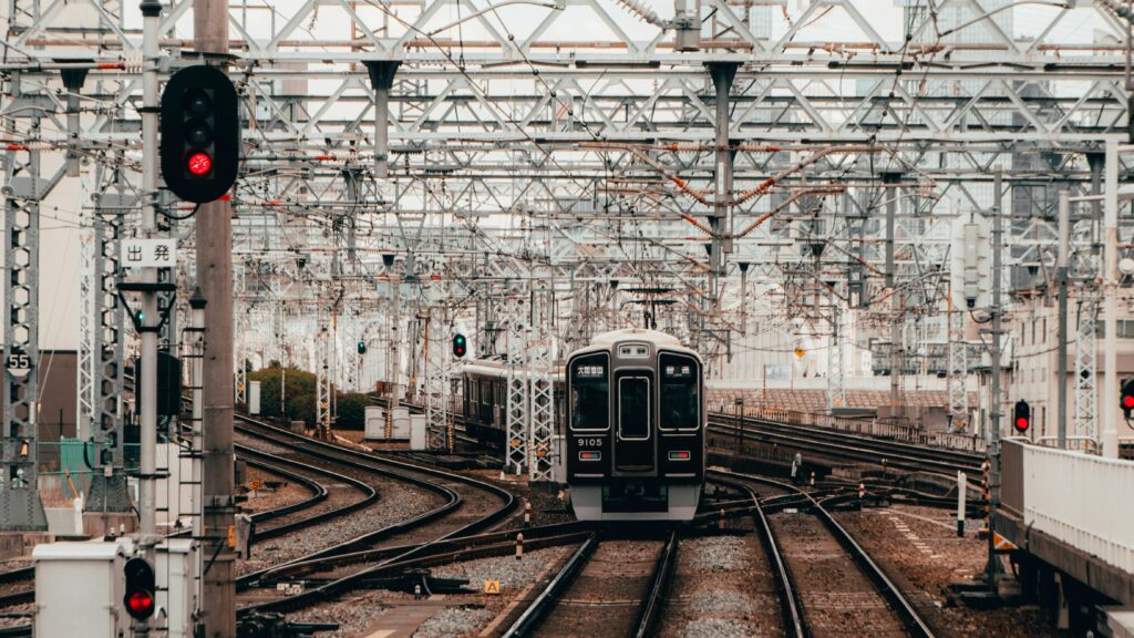 A train navigating through intricate railway tracks and overhead wires in Osaka, Japan.