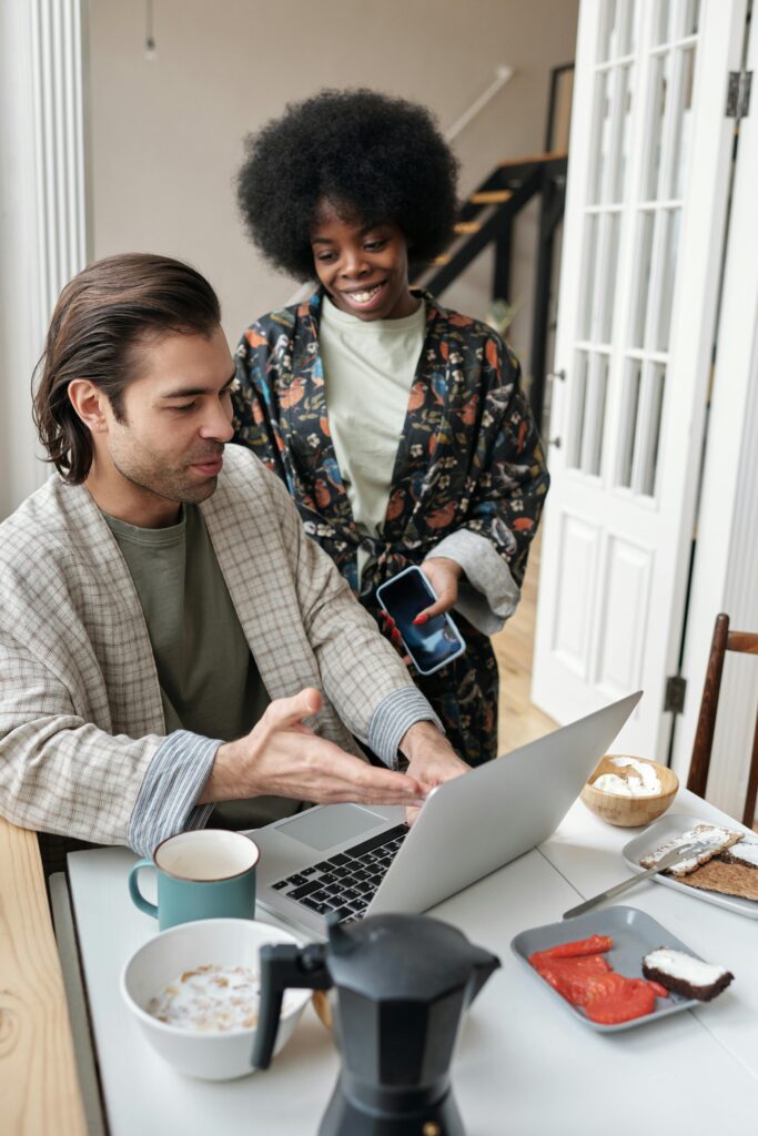 A couple multitasking with breakfast and work from home setup, embracing remote lifestyle.