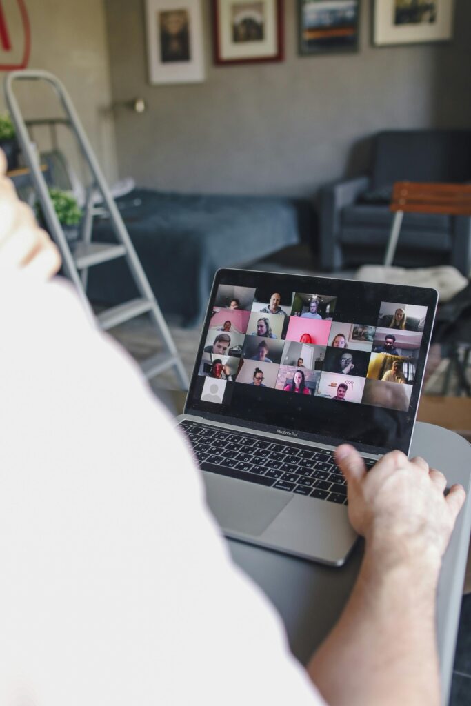 A close-up of a person using a laptop for a virtual meeting indoors.