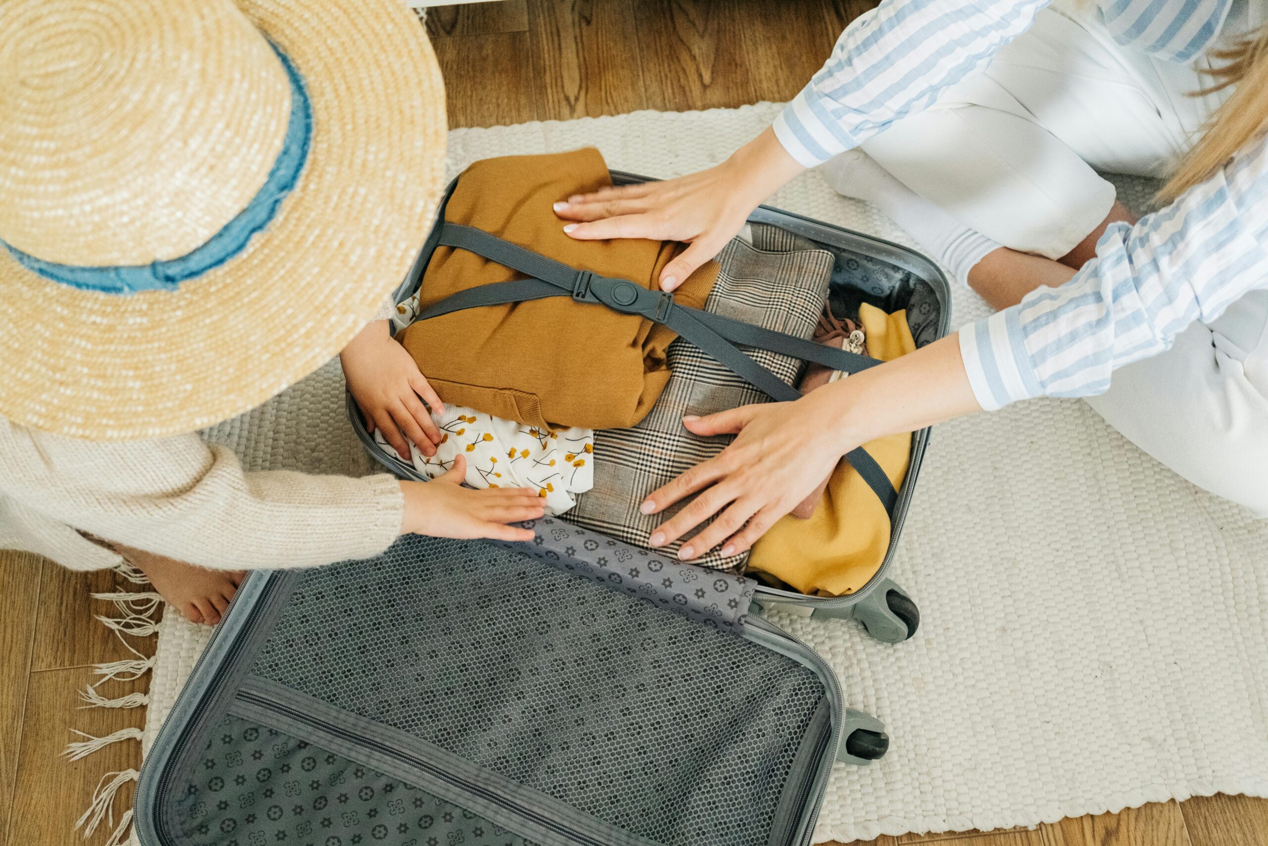 A woman and child pack clothes in a suitcase, preparing for a vacation.