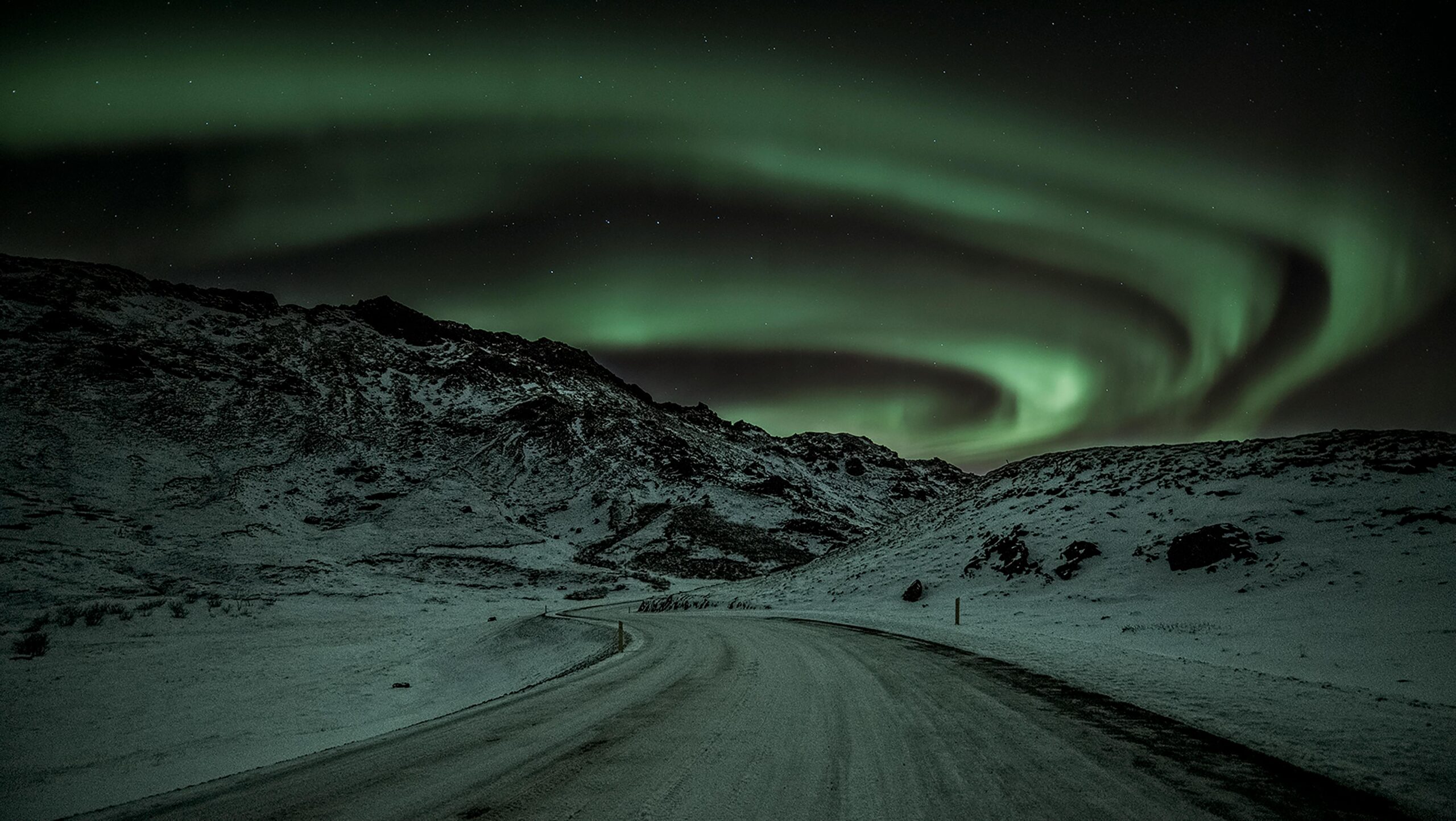 Stunning view of the aurora borealis illuminating the snowy mountains in Iceland at night.