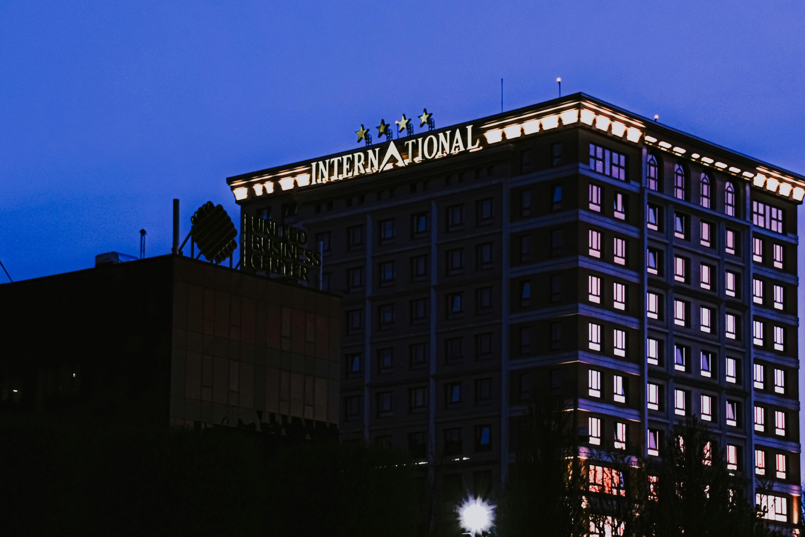 Multistory modern hotel with glowing carnice and light in windows located in city on street in night time against dark sky