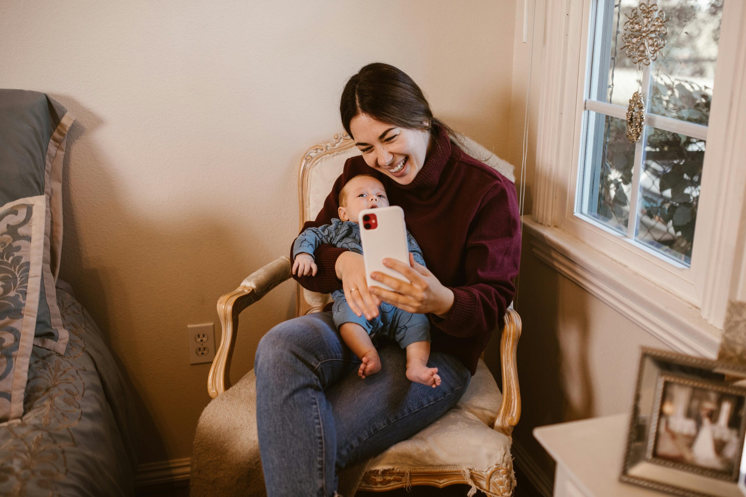 A joyful moment of a mother and her baby capturing memories with a selfie inside their cozy home.