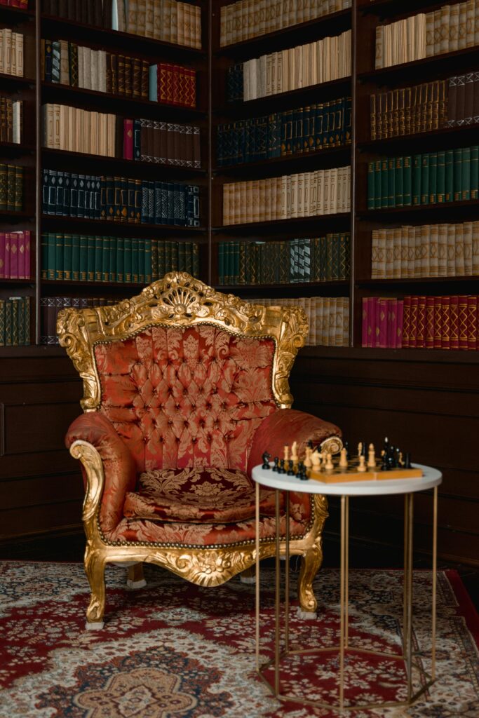 Luxurious library corner featuring an ornate chair and chessboard for a classic ambiance.