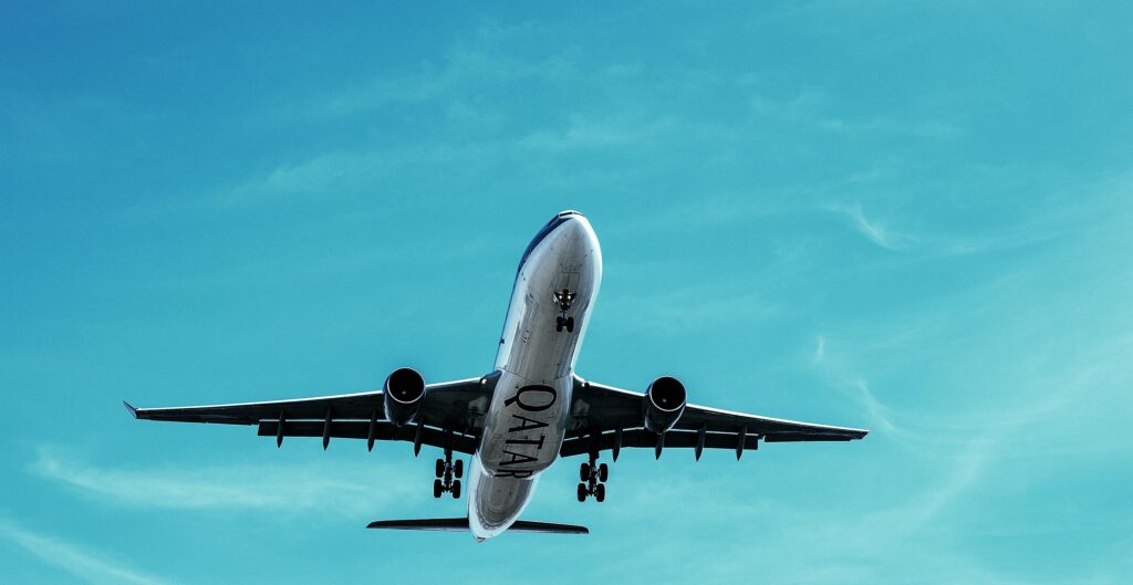 A Qatar Airways commercial airplane takes off into a clear blue sky, showcasing transportation at its finest.