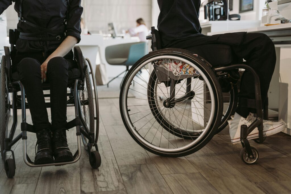 Two people in wheelchairs, indoors, symbolizing accessibility and modern workplace diversity.