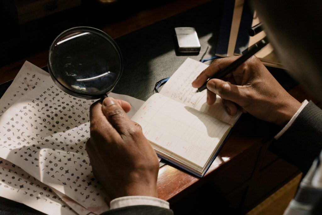 A detective decoding cipher documents with a magnifying glass, notebook in hand.