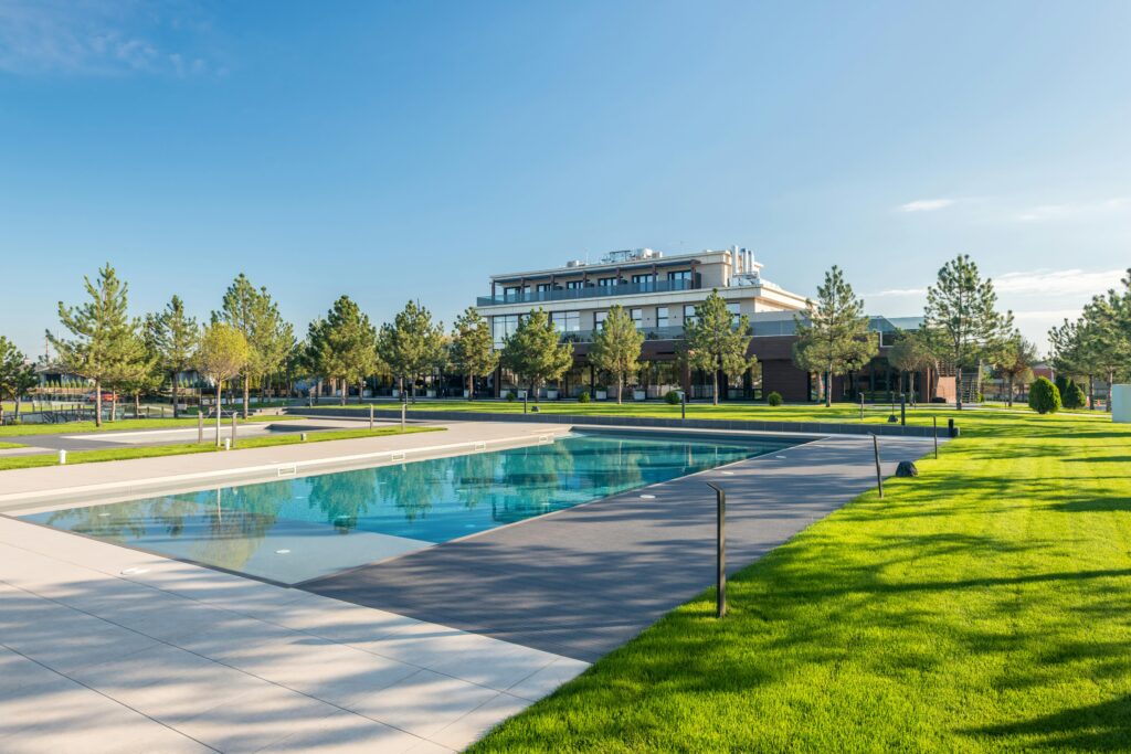 Elegant poolside at a modern resort with lush greenery and clear blue skies, ideal for luxury travel.