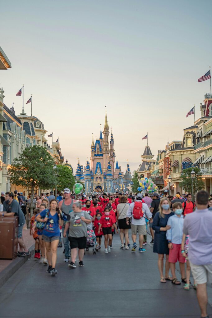 A bustling scene at Disneyland featuring tourists in front of the iconic castle on a sunny day.