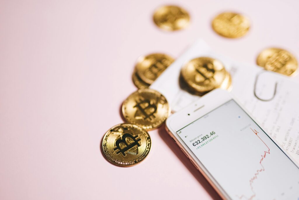 Bitcoin coins with a smartphone displaying financial data, symbolizing cryptocurrency and digital investments.