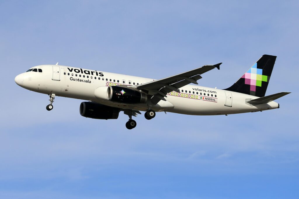 Volaris airplane in flight against clear blue sky, showcasing modern aviation.