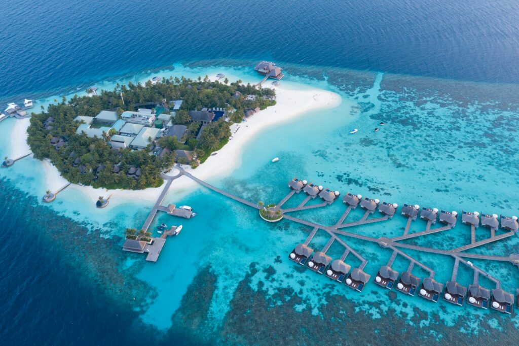 Stunning aerial view of a luxurious tropical island resort in the Maldives, featuring turquoise waters and overwater bungalows.