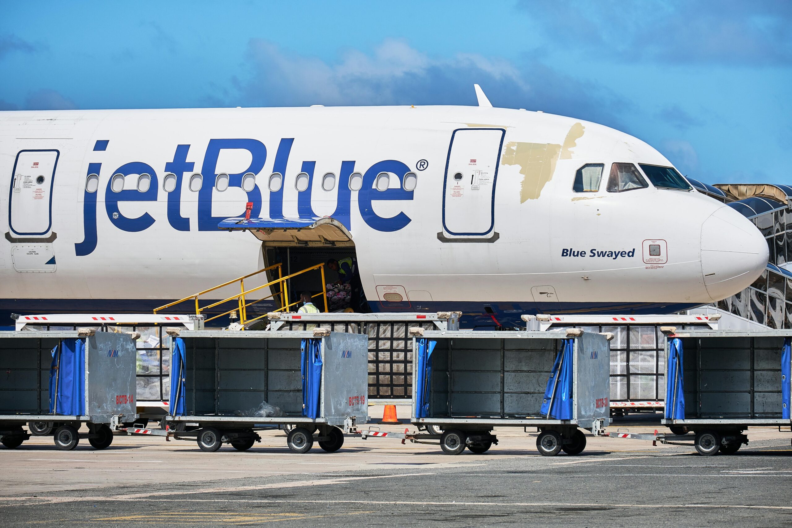 JetBlue Airbus with luggage carts at Punta Cana Airport, Dominican Republic.