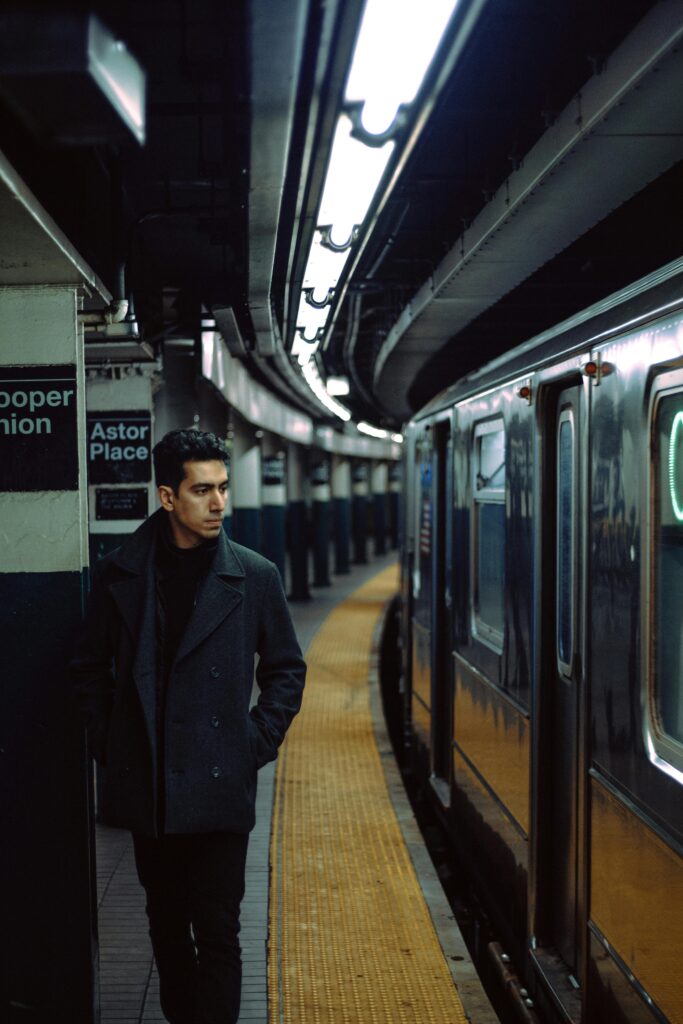 A man stands on the subway platform at Astor Place station, near a subway train.