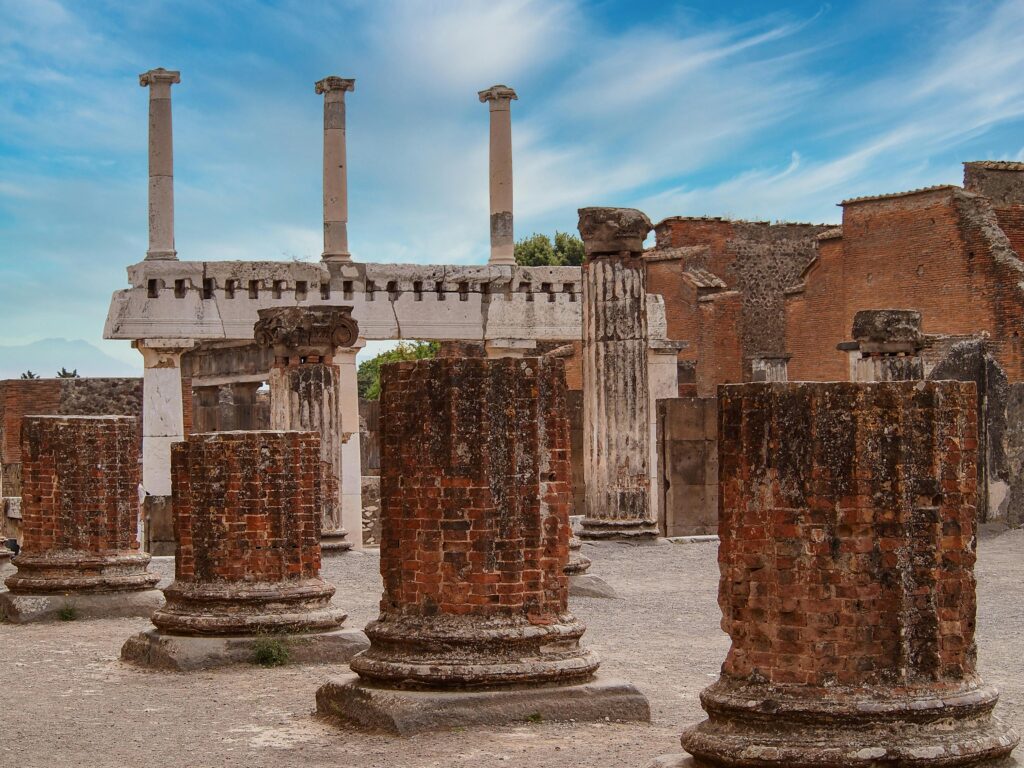 Explore the ancient brick columns and structures of historic Pompeii under a vibrant sky.