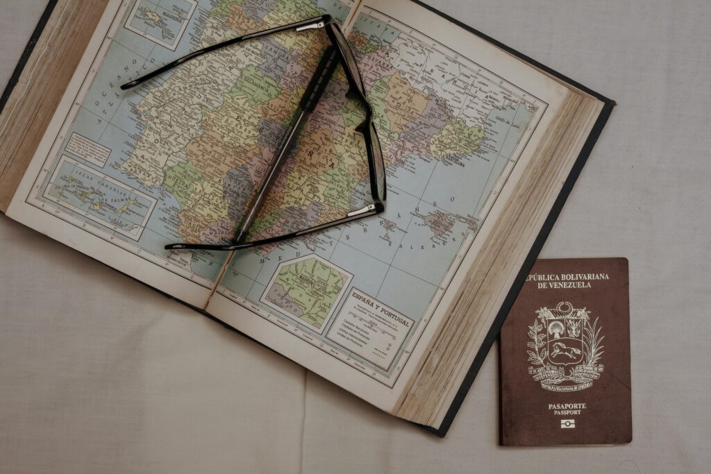 A vintage map of Spain with eyeglasses and a Venezuelan passport, symbolizing travel planning.