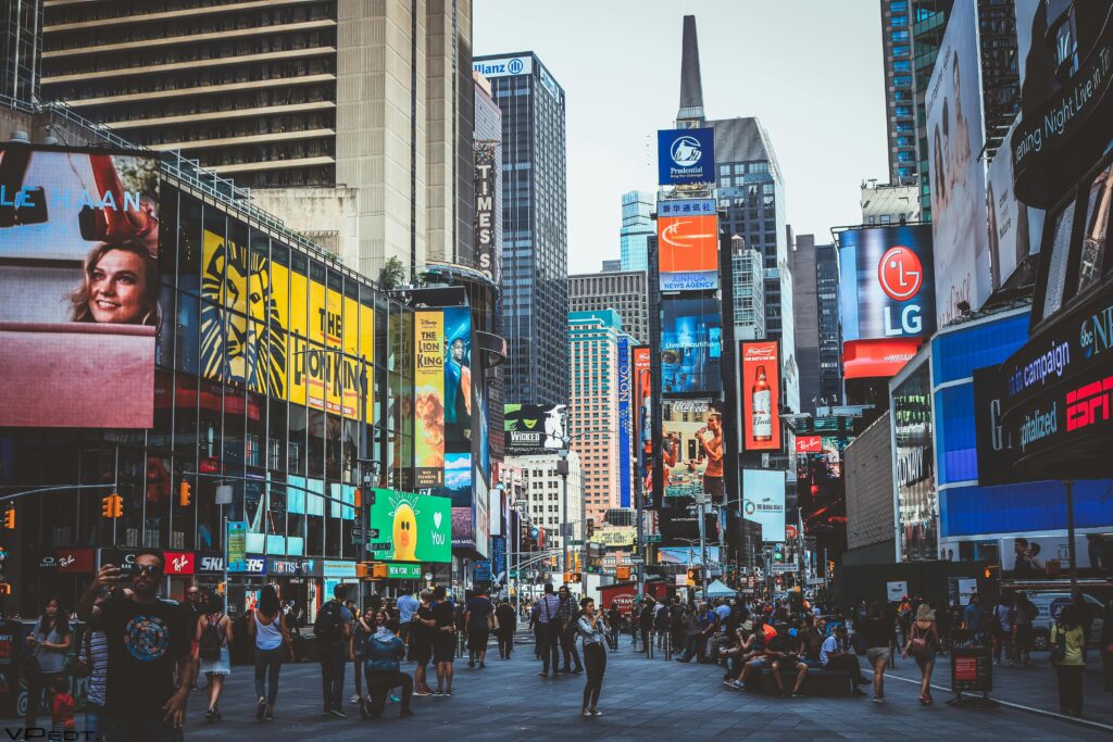 Bustling daytime view of Times Square with crowds, skyscrapers, and iconic billboards in New York City.