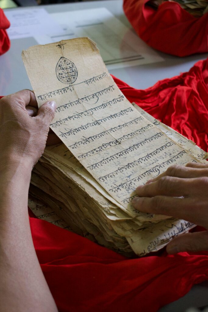 Hands examining an ancient script in Pune, India, showcasing cultural heritage.