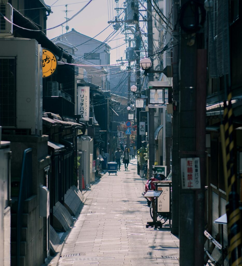 Explore the narrow alleyways of Kyoto, showcasing traditional Japanese architecture under sunny skies.