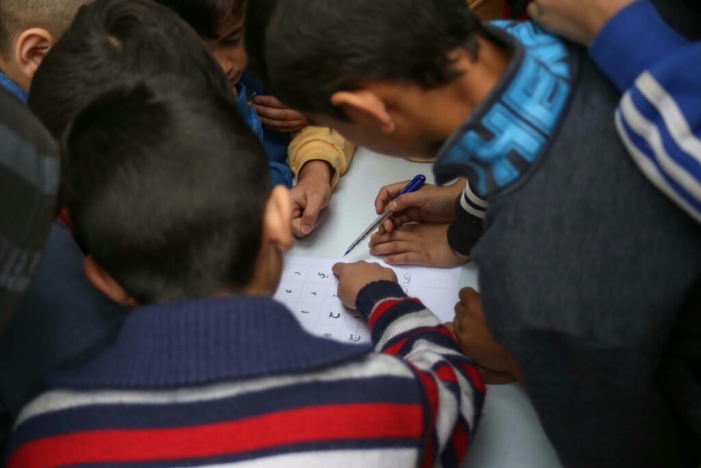 Group of children engaging in learning with a puzzle and pen, fostering teamwork.