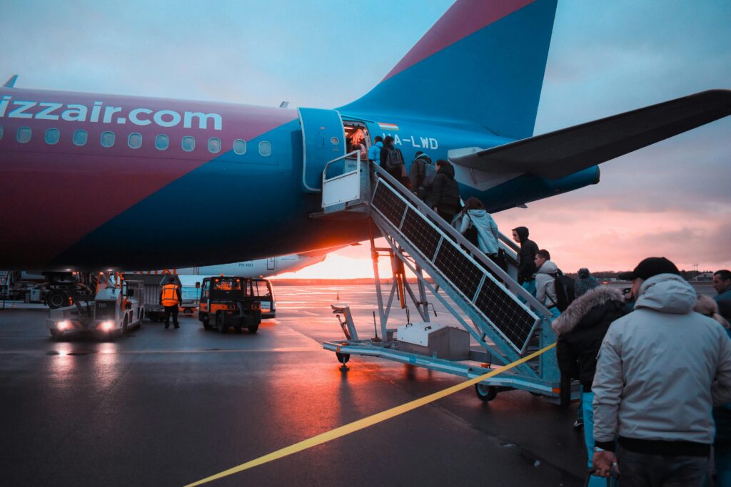 Passengers boarding an airplane at sunset with a vivid sky in the background, capturing a travel moment.