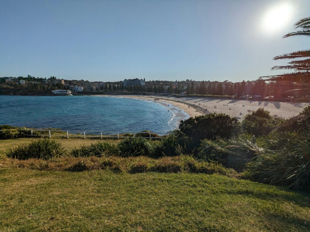 Stunning view of a sandy beach with clear blue water near a coastal town.