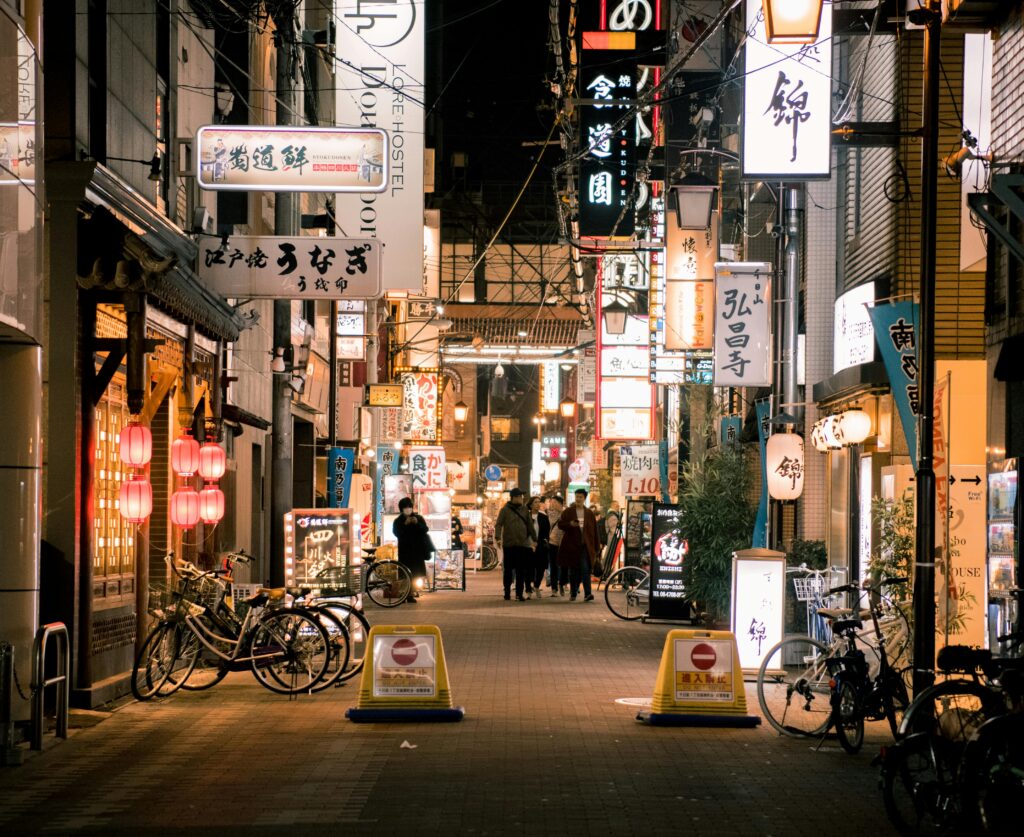 Bustling evening scene of Osaka's vibrant shopping street with illuminated signs and people walking.