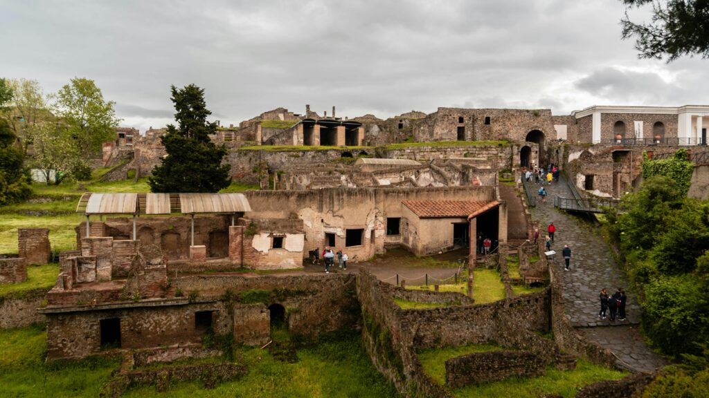 Explore ancient ruins of Pompeii under cloudy skies, capturing rich historical details and lush greenery.