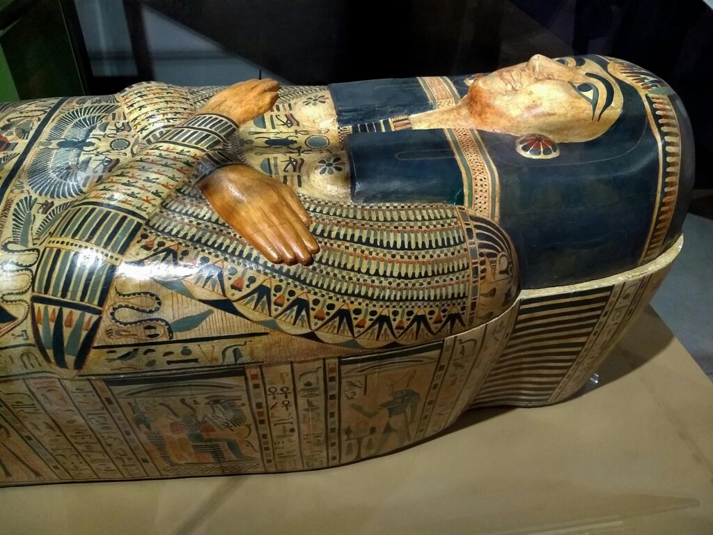 Ancient Egyptian sarcophagus with ornate hieroglyphs and patterns on display indoors.