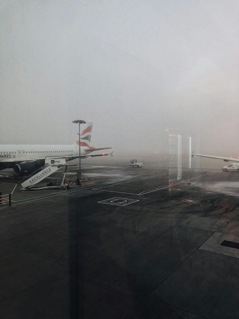 A foggy airport tarmac in Horley, UK, showcasing a parked airliner and ground vehicles.