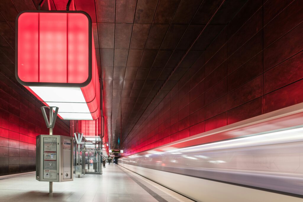 Modern subway station with a sleek design and a fast-moving train. Vibrant red lighting adds a futuristic tone.