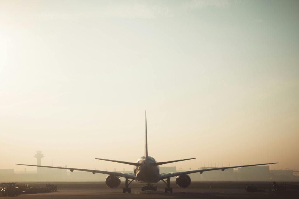 A misty morning scene of a plane on the runway with a hazy sky background, showcasing air travel ambiance.