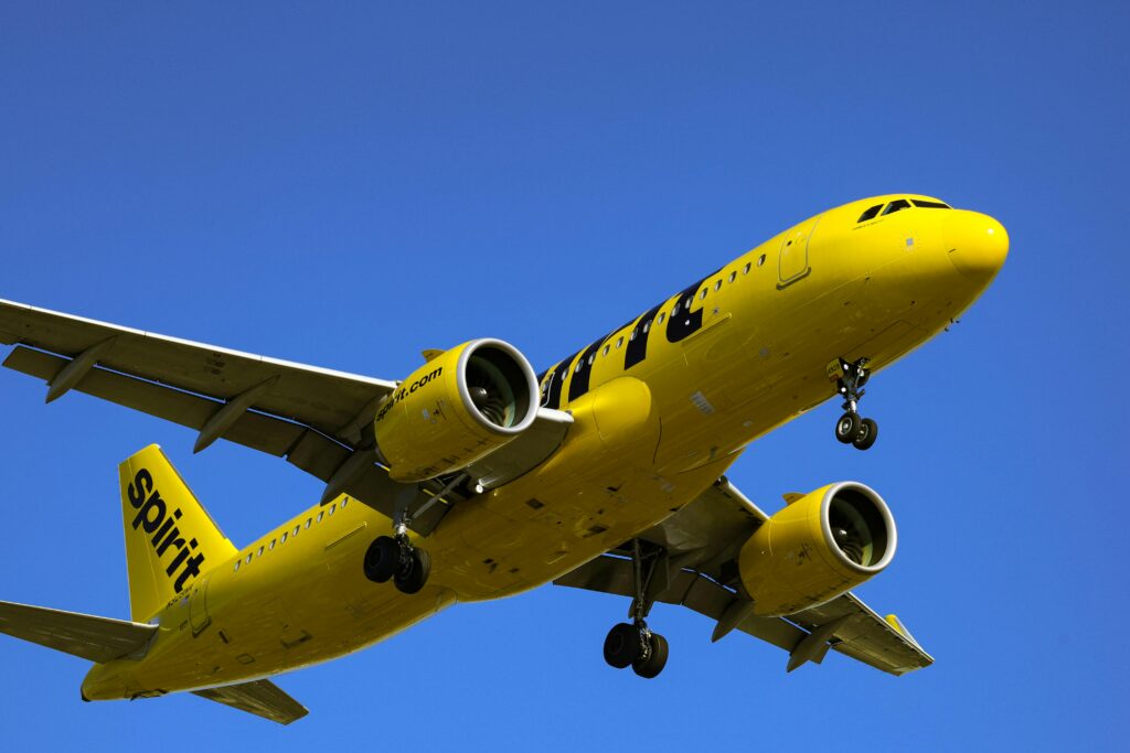 A vivid yellow commercial airplane in flight against a clear blue sky, showcasing dynamic travel and aviation.