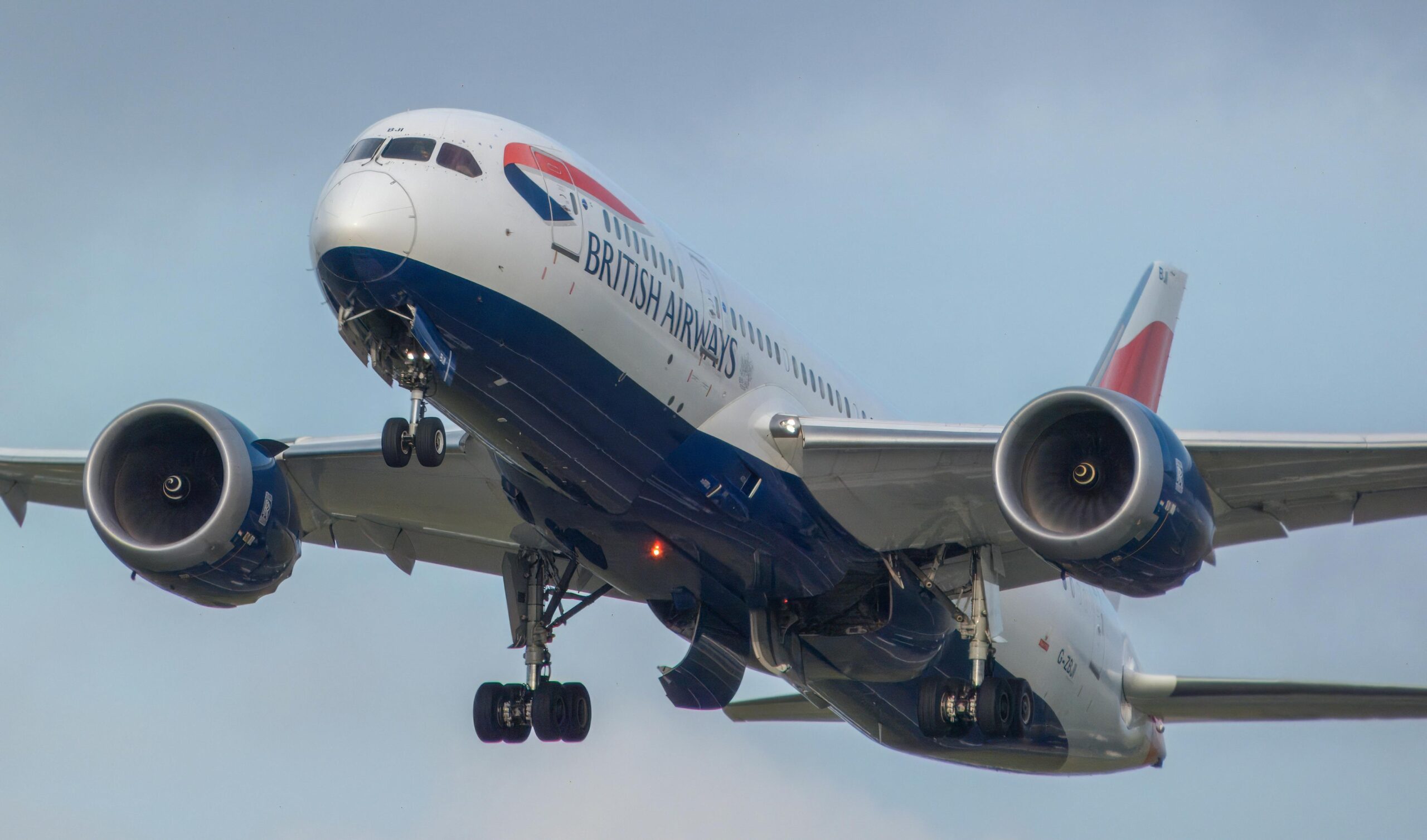 Close-up of a British Airways airplane in flight with a blue sky background.