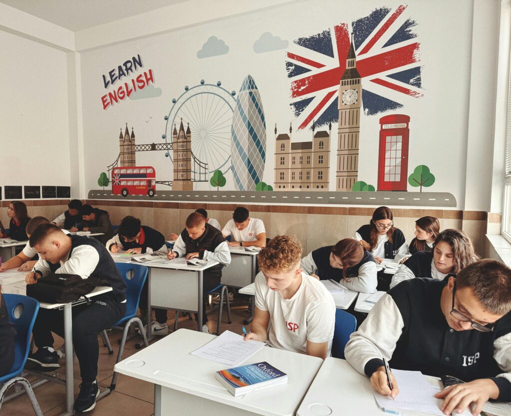 Students studying English in a classroom with British themed decor and mural.