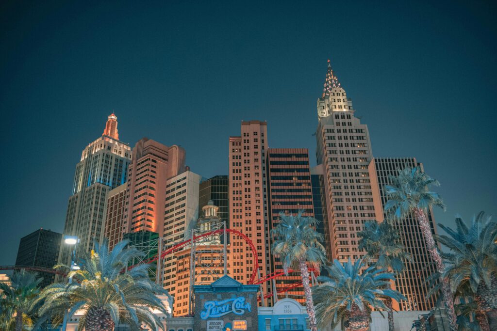 Night view of the Las Vegas skyline featuring iconic skyscrapers and an illuminated roller coaster.