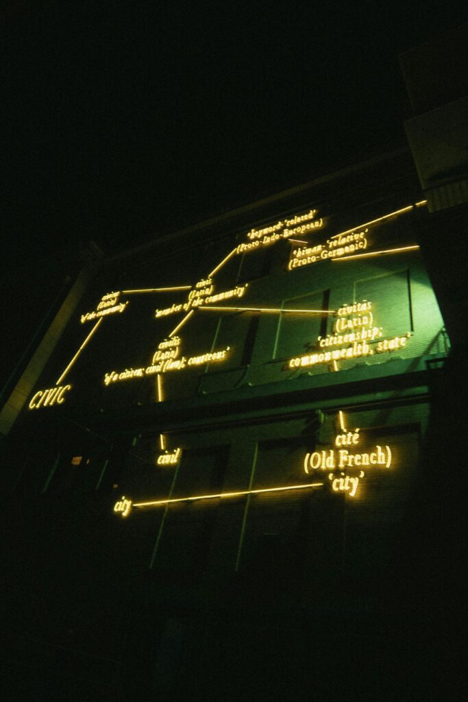 Neon-lit structure at night displaying historical language connections. Modern and abstract lighting art.