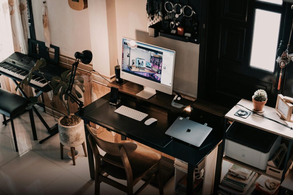 A warm home office setup with a computer, keyboard, and plants.