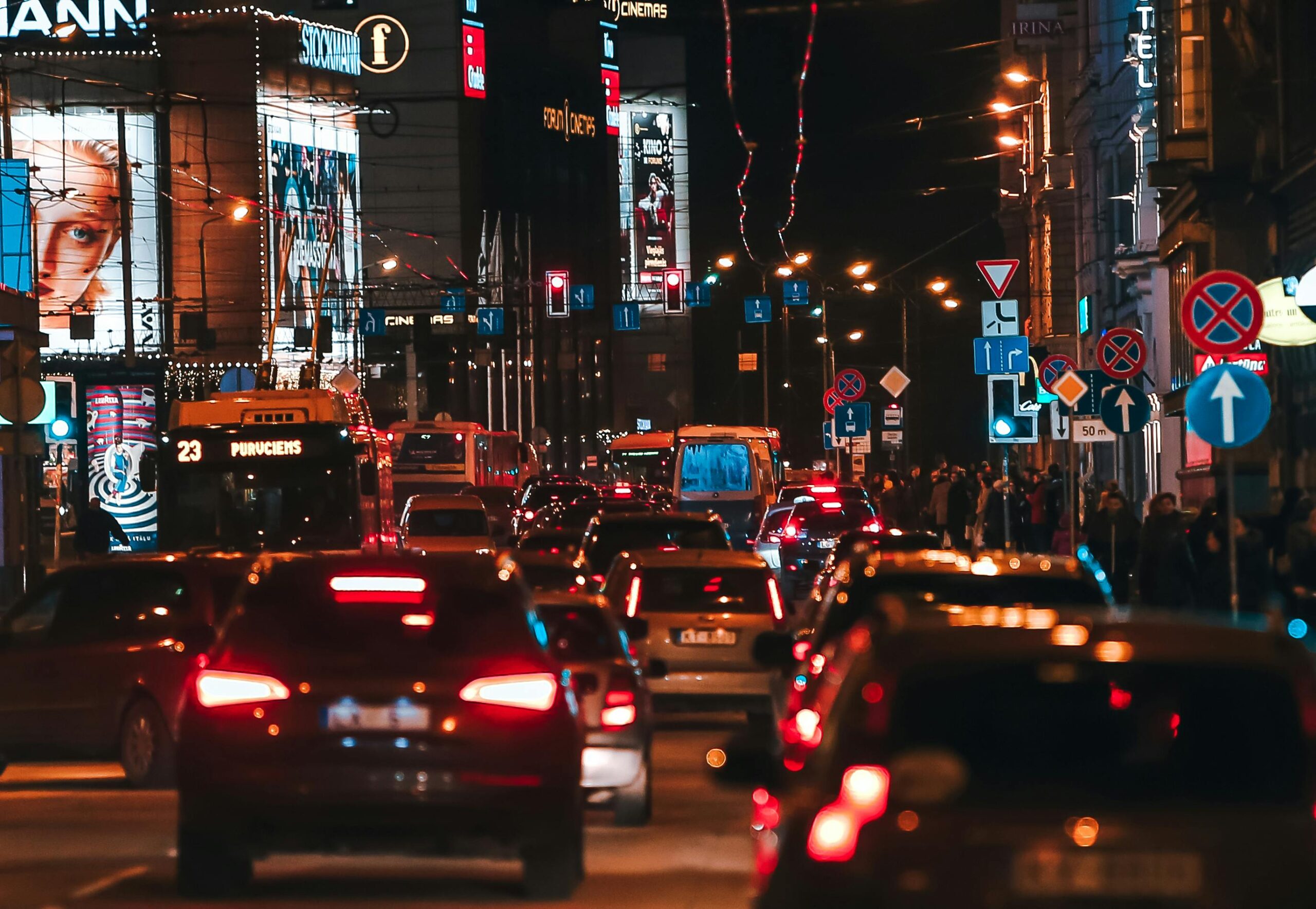 Dynamic urban street scene in Riga, Latvia, showcasing busy night traffic and bright city lights.