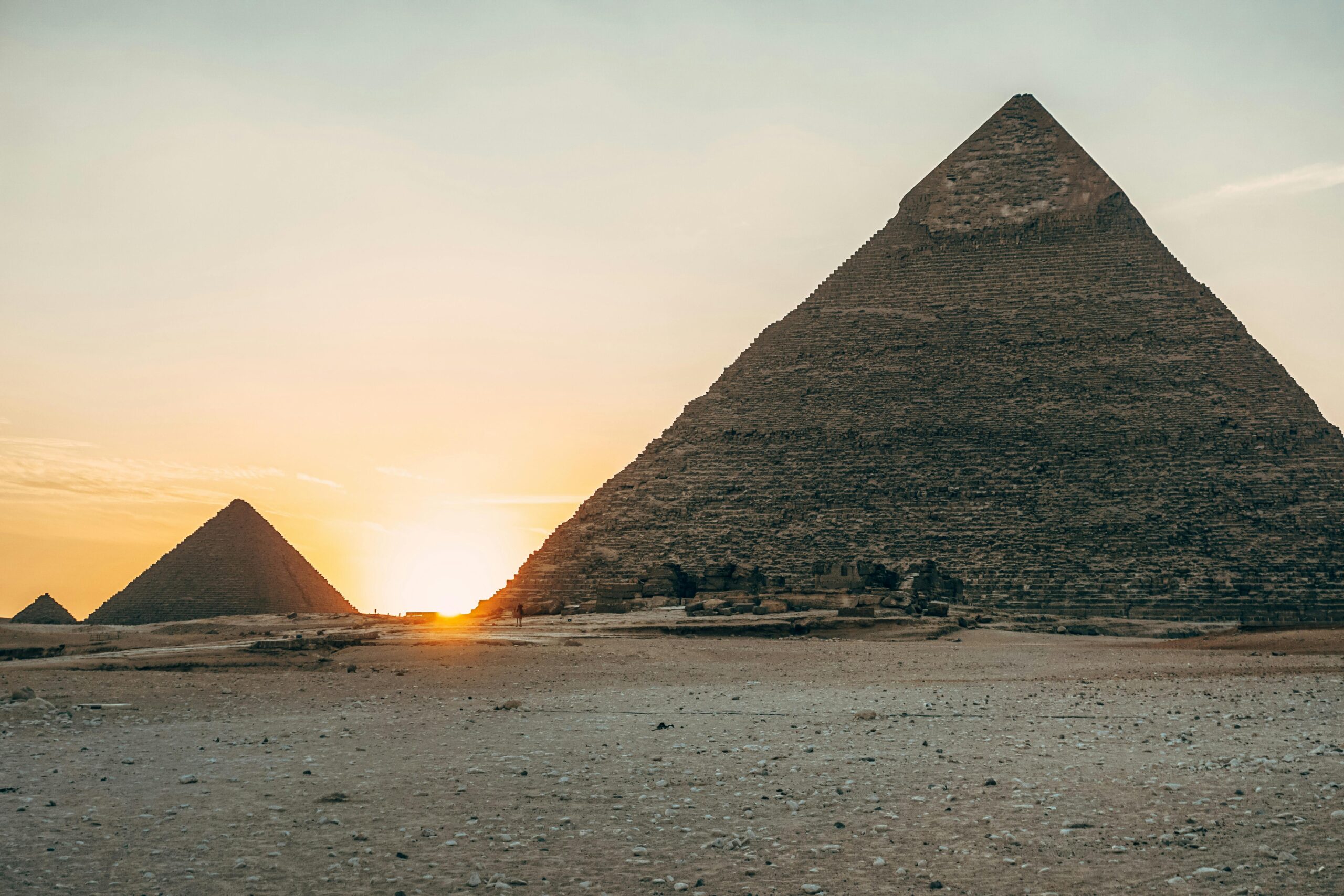 Dramatic sunset view of the iconic Giza Pyramids in Egypt, highlighting their ancient architecture.