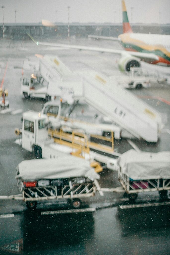 Ground service vehicles and airplane at airport covered in snowfall, capturing winter travel scene.